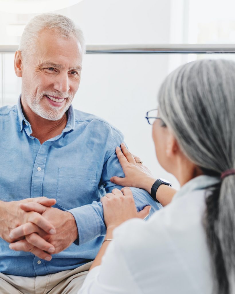 Smiling senior man in wheelchair talking to female doctor